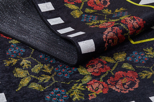 Load image 1 in gallery view. A close-up of the Wildflower Wonderland - Washable Rug - JR587 (Custom Size) shows a folded black corner with a floral pattern in red, pink, and blue flowers, green leaves, and white rectangles—perfect for high-traffic areas.