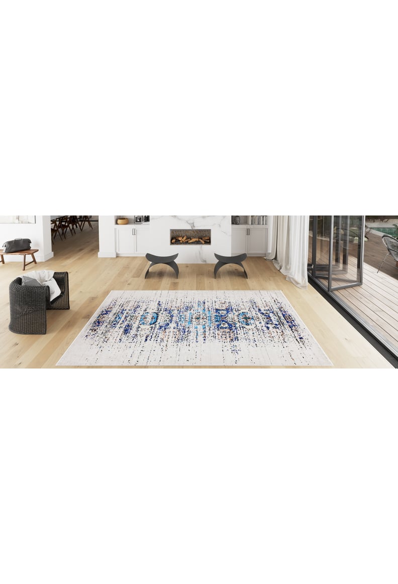 Modern living room with light wood floors, black and gray seating, fireplace, white cabinets, large glass doors to a deck, and the Worn-Out Abstract - Washable Rug - JR339 (Custom Size) in blue—perfect for high-traffic areas.