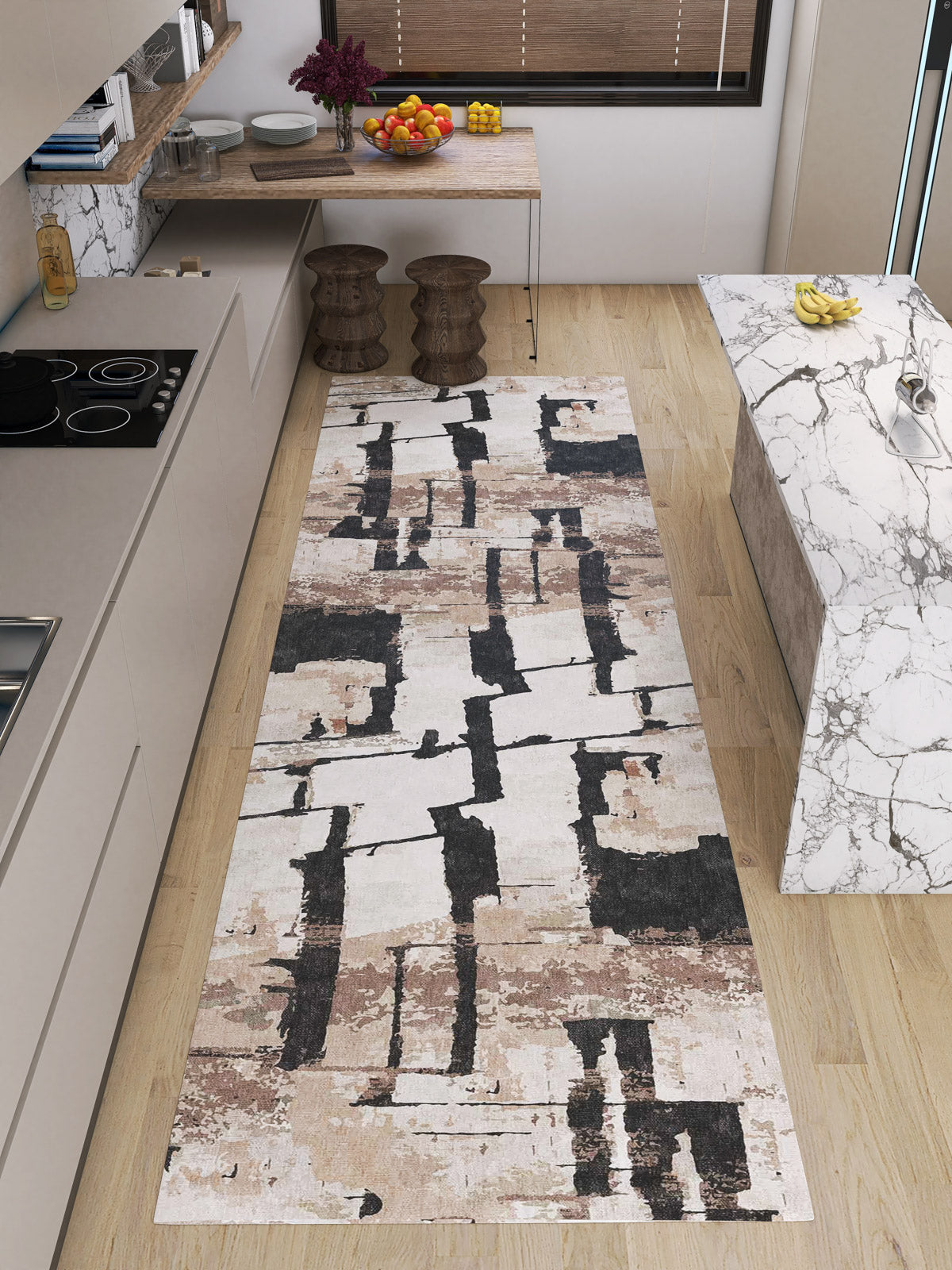 A modern kitchen with light wood floors, a marble island, two wooden stools, and the Woven Memoir - Washable Rug - JRN41 in abstract beige, brown, and black—durable for high-traffic areas. Fruit bowls add a stylish touch to the counters.