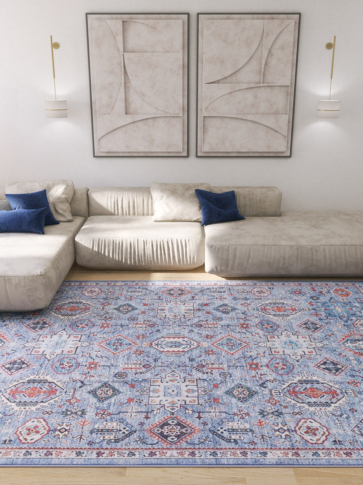 A modern living room with a cream sectional, blue accent pillows, abstract wall art, wall-mounted lights, and the Xanadu Handmade-Design Blue Washable Rug (LCC3013) featuring red and white patterns—ideal for high-traffic wooden floors.