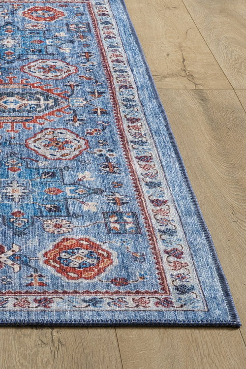 Load image 1 in gallery view. A corner of the Xanadu Handmade-Design Blue Washable Rug - LCC3013, featuring intricate red, white, and light blue geometric patterns, is shown on a light wood floor. Only part of this custom-size flat weave rug is visible in the image.