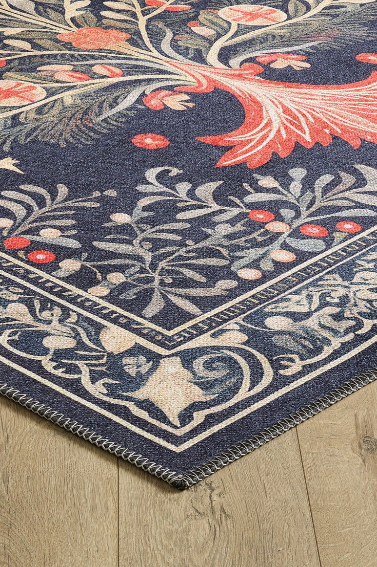 Corner of the Xmas Tree Washable Area Rug - MDJ005, featuring a dark blue background, cream floral and vine patterns with red accents, and a detailed border, displayed on light wood flooring—ideal for high-traffic spaces.