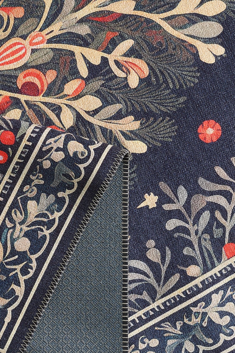 Close-up of the Xmas Tree Washable Area Rug - MDJ005 featuring a multicolor botanical design in red, cream, and green on dark blue; one corner is folded to display the reverse side and stitched edge—ideal for high-traffic spaces. Custom sizes available.