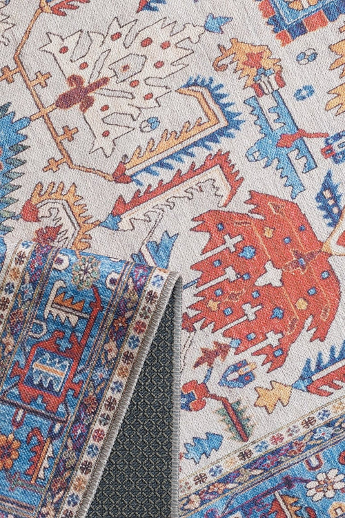 Load image 1 in gallery view. A close-up of the Yonder Blue Cream Washable Rug (LCC3045) shows its red, blue, orange, and cream patterns. One corner folds to reveal a dark non-slip backing—ideal for high-traffic spaces and easy care as a washable rug.