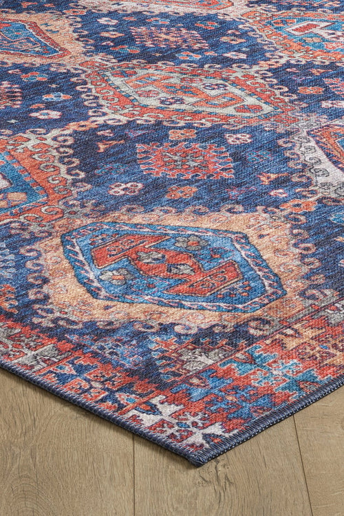 Bild 1 in Galerieansicht laden. A close-up of the Zephyro Kilim-Design Washable Rug (LCC3008), featuring intricate geometric and floral patterns in blue, red, orange, and cream on a wooden floor—ideal for high-traffic areas.