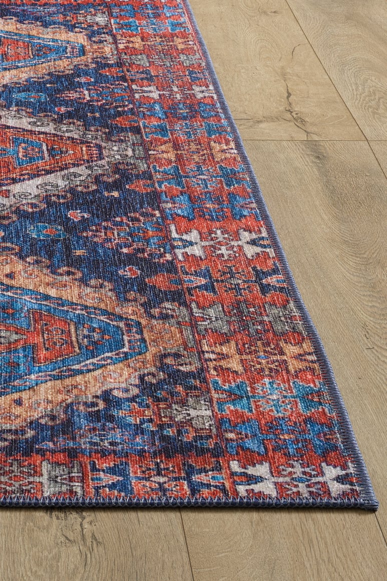 A close-up of the Zephyro Kilim-Design Washable Rug - LCC3008 shows its red, blue, and beige geometric patterns on a light wooden floor—ideal for allergy-sensitive homes and busy spaces.