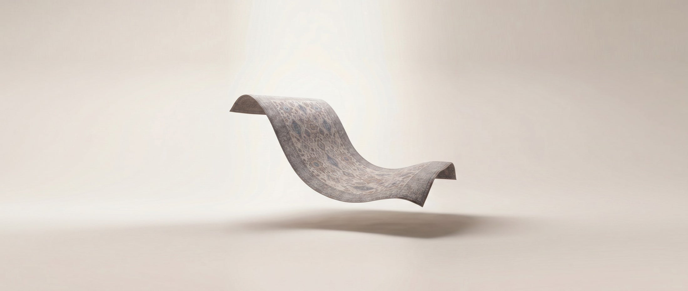 A floating, wavy rectangular gray panel or sheet with a subtle textured pattern, photographed against a soft warm beige studio background with a faint shadow below.