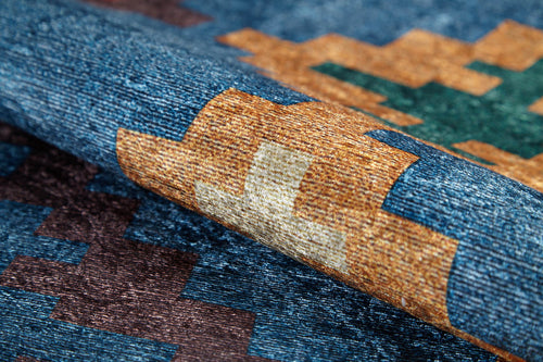 Load image 1 in gallery view. A close-up of the Nomad's Mirage - Washable Rug - JR5032 (Custom Size) shows its geometric pattern in blue, brown, gold, green, and beige. Folded to showcase texture and color, this washable rug is ideal for allergy-sensitive or high-traffic areas.