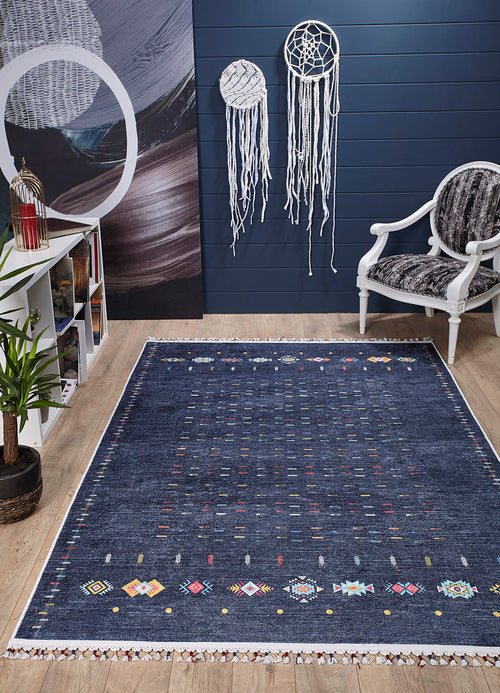 Load image 1 in gallery view. A modern room with the Wanderer's Way - Washable Rug - JR5101 (Custom Size) in blue, a white armchair with dark cushion, dreamcatchers on a navy wall, white shelf with books and decor, potted plant, and light wood floor—ideal for high-traffic spaces.