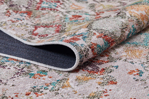 Load image 1 in gallery view. A close-up of the Aged Mosaic - Washable Rug - JR1096 highlights its vibrant red, green, yellow, and blue patterns on a light background. The folded corner reveals the dark, textured underside of this flat weave rug.