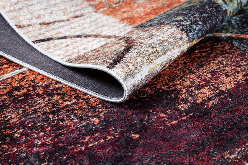 Load image 1 in gallery view. A close-up of the Angular Beauty - Washable Rug - JR2002 displays its abstract multicolor pattern with red, orange, brown, and beige hues and a folded edge revealing texture and backing—perfect for stylish high-traffic spaces.