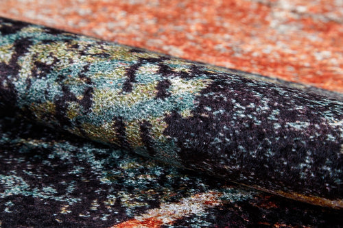 Load image 1 in gallery view. A close-up of the Angular Beauty - Washable Rug (JR2002), featuring a rolled, textured surface with an abstract pattern in black, green, yellow, orange, and blue. Its soft, plush fabric is ideal for high-traffic areas and easy to clean.