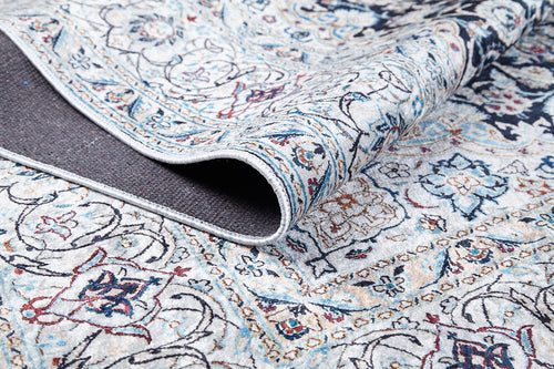 Load image 1 in gallery view. A close-up of the Antique Enchantment - Washable Rug - JR1686 shows intricate blue, red, and beige flat-weave patterns with a folded corner revealing its dark backing. Floral and geometric designs offer an allergy-friendly touch.