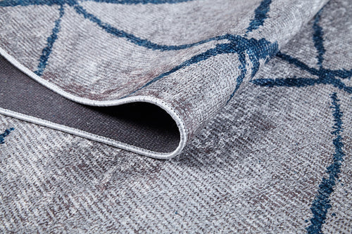 Load image 1 in gallery view. Close-up of the Arabesque Trellis - Washable Rug - JR1732 in textured gray and blue, slightly lifted to reveal the underside and edge stitching. Features an abstract, intersecting line pattern—great for allergy-sensitive or high-traffic spaces.