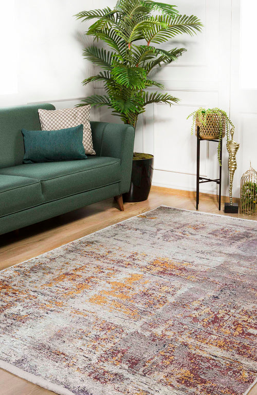 Load image 1 in gallery view. A modern living room featuring a green sofa with decorative pillows, a large leafy plant, small table with potted plants, and the Artistic Abstraction - Washable Rug - JR775 in shades of gray, yellow, and burgundy on a wooden floor.
