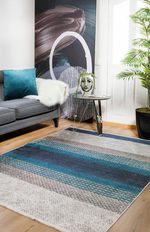 Load image 1 in gallery view. A modern living room with a gray sofa, teal pillow, white throw, abstract wall art, small glass table with face planter, large green plant, and the Artistic Angles - Washable Rug - JR908—ideal for high-traffic areas—on wood floors.
