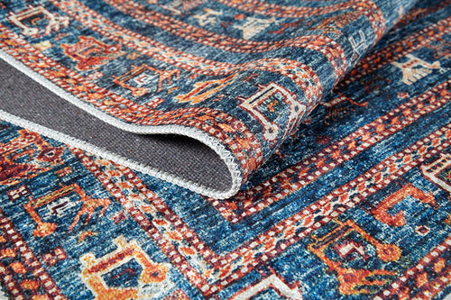 Load image 1 in gallery view. A close-up of the Berber Beauty - Washable Rug - JR5092 in vibrant blue with bold red and cream geometric patterns. The folded corner reveals sturdy stitching and texture—ideal for high-traffic areas.