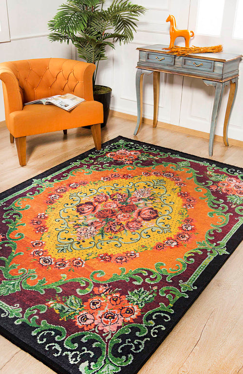 Bild 1 in Galerieansicht laden. The Blossoming Garden - Washable Rug - JR150, featuring a vibrant floral pattern, lies on a light wood floor near an orange armchair, a small blue table with a horse figurine, and lush green plant against white paneled walls.