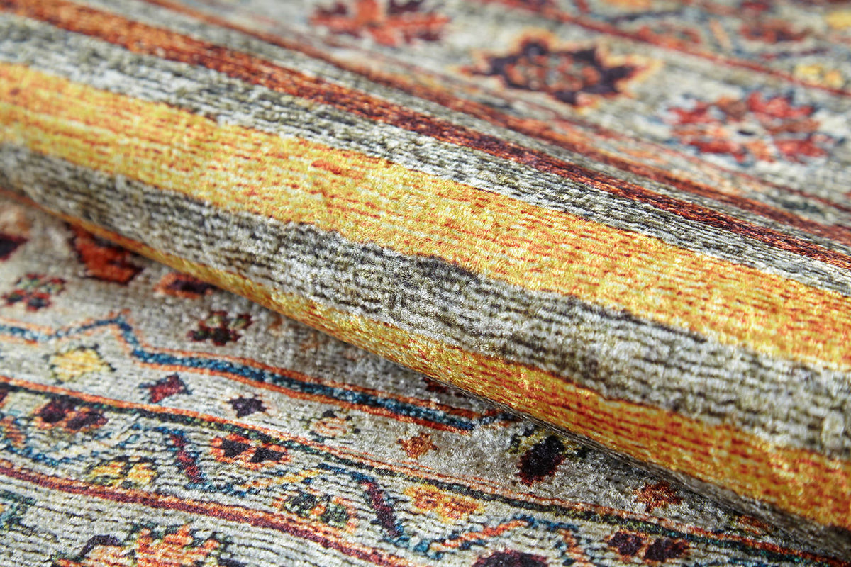 A close-up of the Bohemian Bouquet - Washable Rug - JR5090 highlights its allergy-friendly, multicolor weave with detailed yellow, gray, and orange floral and geometric patterns. The intricate texture is visible as the rug is slightly rolled.