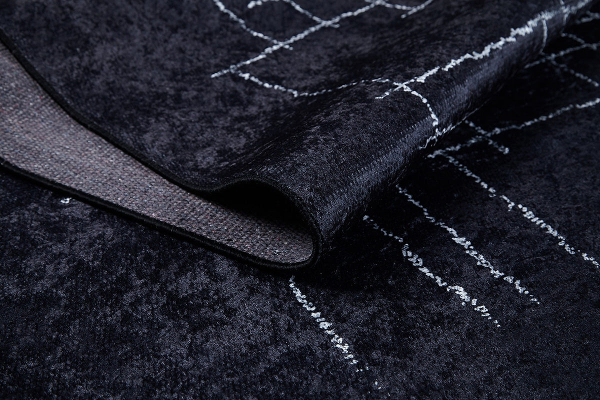 Close-up of the Bohemian Illusion - Washable Rug - JR1953, a black flat weave with a white geometric line pattern; the corner is folded to show its washable backing.