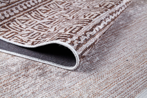 Load image 1 in gallery view. A close-up of the Bohemian Treasure - Washable Rug (JR1586) highlights its geometric brown and beige pattern, with the edge lifted to show the underside—perfect for allergy-sensitive or high-traffic textured areas.
