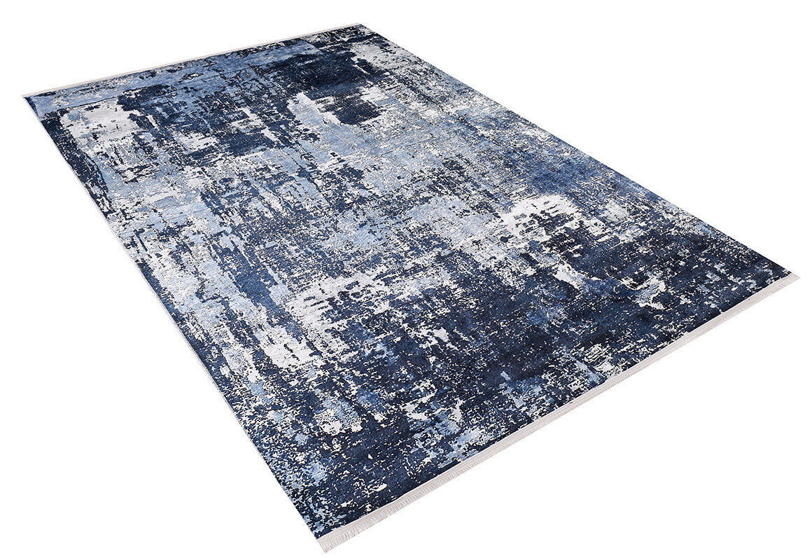 The Bold Blooms - Washable Rug - JR836 is a rectangular blue rug with an abstract, textured pattern in blue, white, and gray. Shown angled on a white background, it's washable and ideal for high-traffic areas.