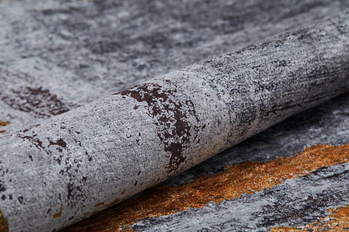 A close-up of the Bold and Chic - Washable Rug - JR1198, showing its textured stone-like pattern in gray, brown, and orange tones. Ideal for allergy-sensitive spaces, this rug offers a rough look with natural, earthy hues.