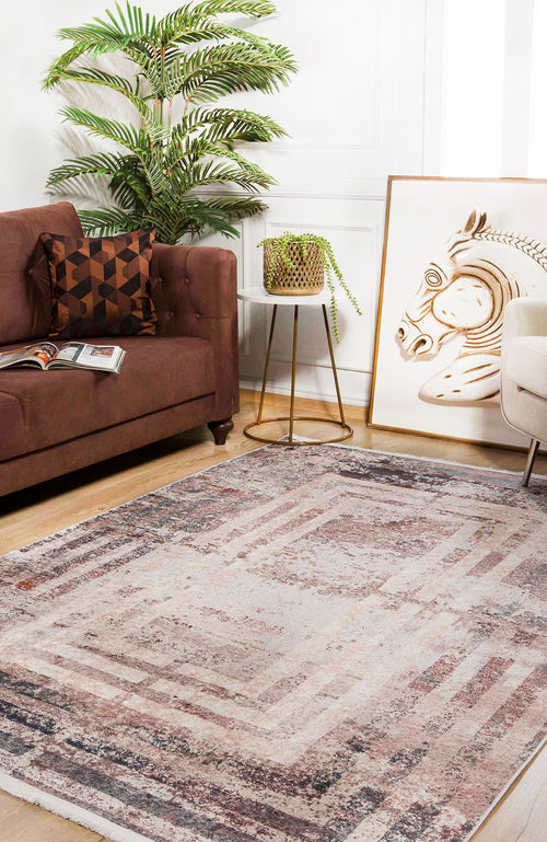 Load image 1 in gallery view. A cozy living room features a brown sofa, geometric pillow, plant, small side table, zebra art, cream armchair, and the Bold and Geometric - Washable Rug - JR1410 (Outlet) US in bronze and brown on wood floors—ideal for high-traffic areas.