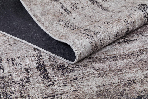 Load image 1 in gallery view. A close-up of the Borderline Chic - Washable Rug - JR1156 shows its textured, neutral tones and abstract design, with a folded corner revealing the durable dark backing—perfect for high-traffic areas.