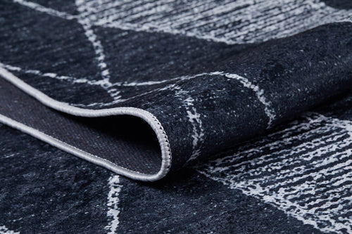 Load image 1 in gallery view. A close-up of the Byzantine Beauty - Washable Rug - JR1037, featuring a folded dark blue surface with a white geometric pattern and visible stitched edging. The texture and design details are clear, perfect for high-traffic areas.