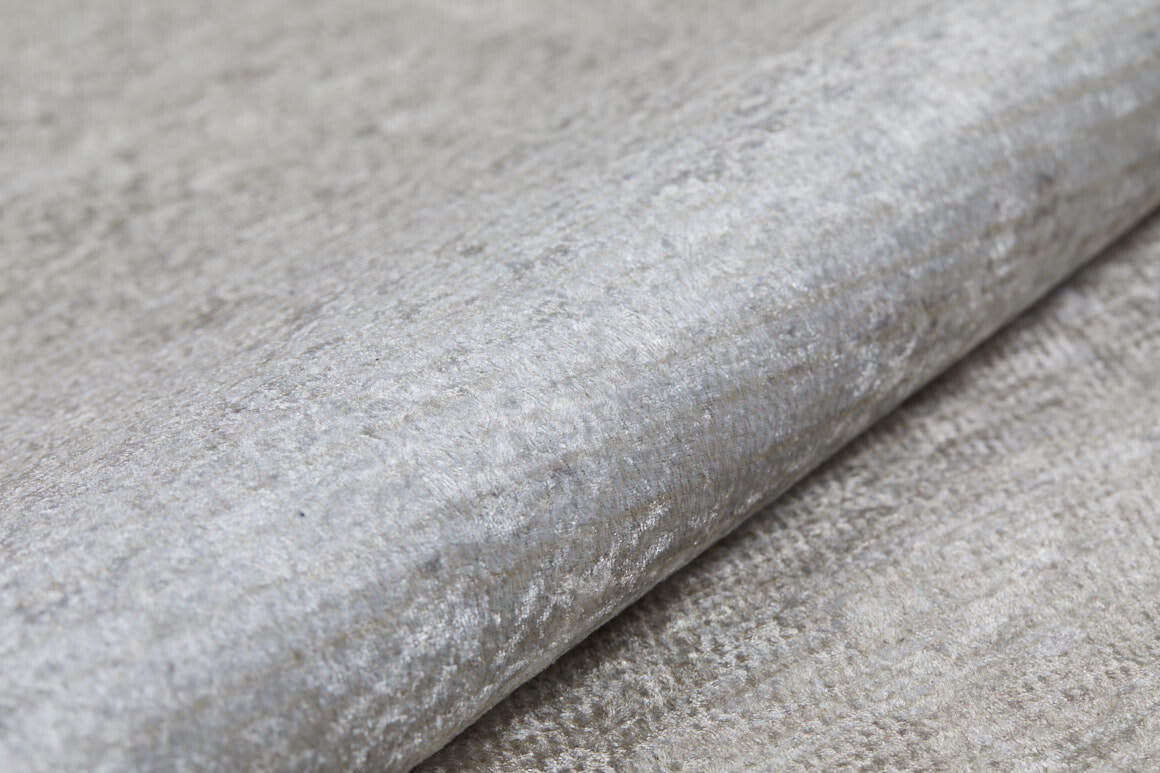 A close-up of Cinnamon Swirl - Washable Rug - JR425 shows its gray, textured, metallic-finish surface—resembling recycled fiber and crafted for high-traffic areas, combining durability with washable convenience.
