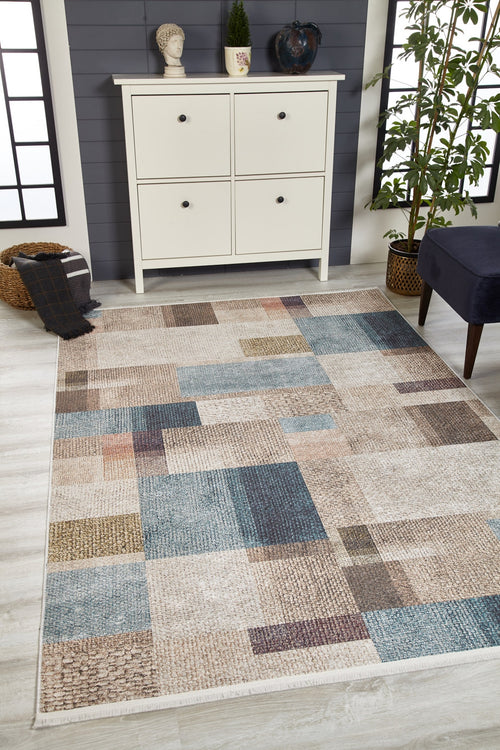 Load image 1 in gallery view. The Classic Check - Washable Rug - JR1955, featuring a beige and blue geometric square pattern, is displayed on a light wood floor before a white cabinet with decor and a potted plant—perfect for high-traffic areas.