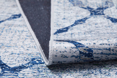Load image 1 in gallery view. A close-up of the Classic Trellis - Washable Rug - JR710 features blue geometric patterns, with a corner folded to reveal its textured, dark non-slip backing.