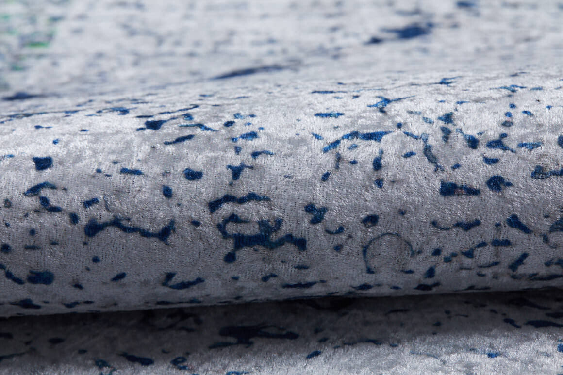 Close-up of the Classic Trellis - Washable Rug - JR710 in soft, light gray flat weave with textured surface and irregular navy blue speckled patterns. Slight folding adds charm, making it ideal for a modern living room.