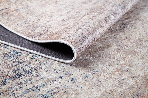 Load image 1 in gallery view. A close-up of the Copper Glow - Washable Rug - JR1700 shows its cream and beige surface with subtle blue and grey specks, a dark non-slip backing, and a soft texture—ideal for high-traffic areas.