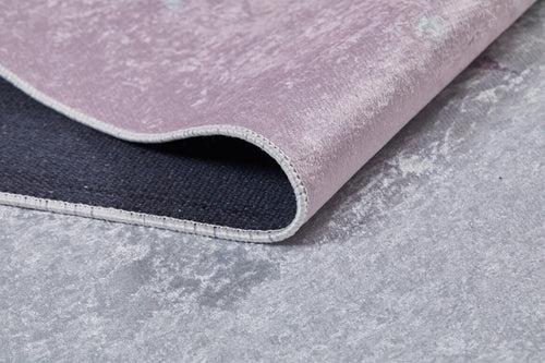 Load image 1 in gallery view. A close-up of the Cosmic Naptime - Machine-Washable Rug JRC032 featuring a soft pink flat weave, black accents, curved edge, and visible stitching, displayed on a gray textured surface.