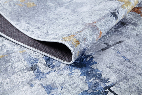 Bild 1 in Galerieansicht laden. A close-up of the Cross Country - Washable Rug - JR1753 shows its gray, blue, and brown abstract pattern with a folded corner revealing the dark backing—durable for high-traffic areas and easy to maintain as a washable rug.