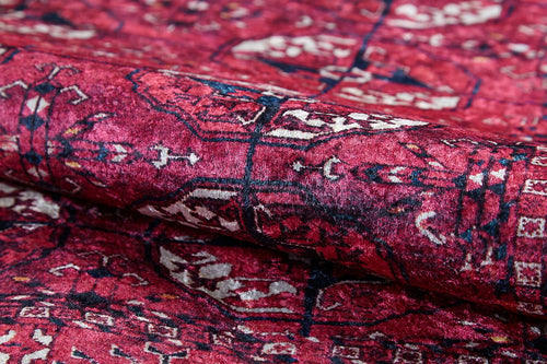 Load image 1 in gallery view. Close-up of the Desert Dreamscape - Washable Rug - JR1940 in soft pink, featuring intricate white, red, and black geometric and floral designs; partially folded to highlight its detailed texture and washable quality.