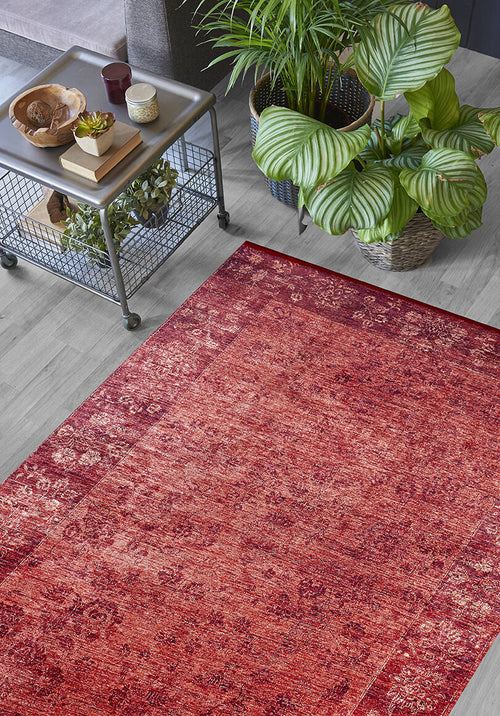 Load image 1 in gallery view. The Dynasty Dream - Washable Rug - JR160 with a red oriental pattern lies on a light wood floor beside a metal table with décor and potted plants, adding warmth and style to this modern living space.
