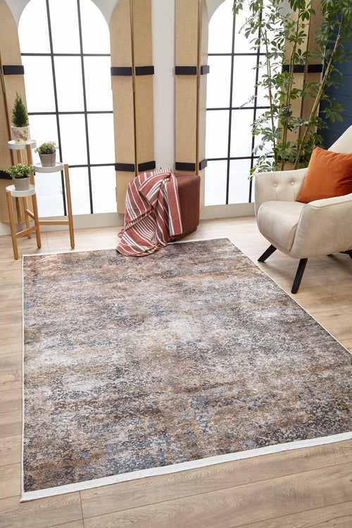 Bild 1 in Galerieansicht laden. A modern living room features the Elegant Leaf - Washable Rug - JR1945 in bronze and brown on wooden floors, a beige armchair with an orange pillow, potted plant, side table with small plants, and soft light—perfect for high-traffic areas.