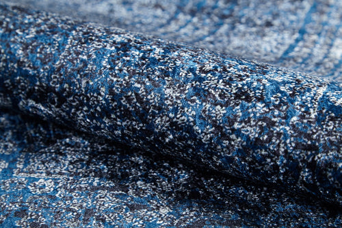Load image 1 in gallery view. A close-up of the Elegant Vine - Washable Rug (JR1847) rolled up, highlighting its blue and gray flat weave texture and intricate vine-inspired design.