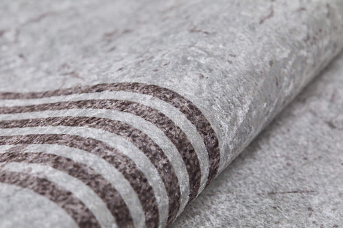 Load image 1 in gallery view. Close-up of Elegant and Chic - Washable Rug - JR1509: a light gray, textured surface with dark wavy lines. Slightly rolled, it offers a soft, fabric-like feel and durability perfect for high-traffic areas.