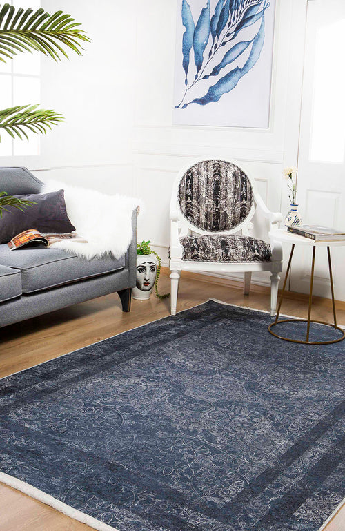 Load image 1 in gallery view. A modern living room with a gray sofa, patterned armchair, round side table, blue leaf wall art, and the Elegant and Modern - Washable Rug - JR1297—perfect for high-traffic areas. A decorative face vase sits near the sofa.