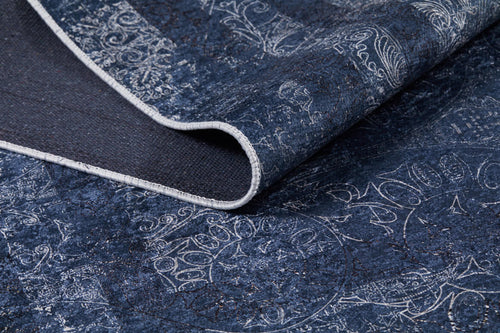 Load image 1 in gallery view. Close-up of the Elegant and Modern - Washable Rug - JR1297 in dark blue with white abstract patterns. The corner is folded to reveal the weave, highlighting its durability and suitability for high-traffic areas.