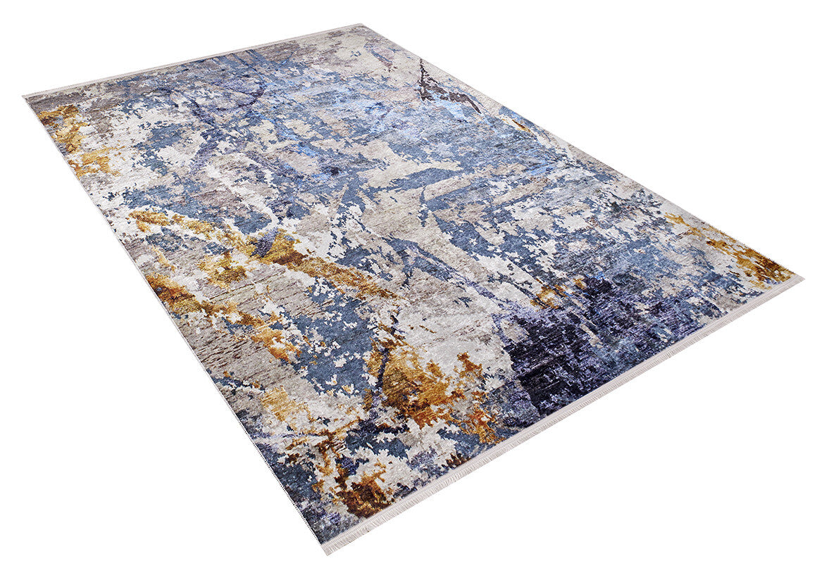 The Enigmatic Elegance - Washable Rug - JR787 is a rectangular blue rug with abstract gray, beige, and gold accents. Ideal for high-traffic areas, it features a blend of light and dark patches and is shown against a white background.