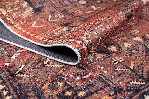 Load image 1 in gallery view. A close-up of the Ethereal Elegance - Washable Rug - JR1651 (Outlet) US shows its intricate bronze and brown design, partially folded to display the textured dark gray underside—ideal for high-traffic areas.