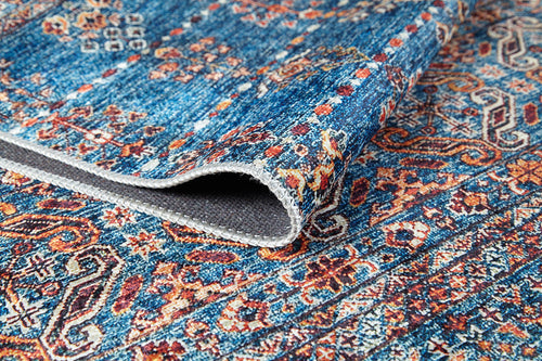 Load image 1 in gallery view. A close-up of the Ethereal Essence - Washable Rug - JR5087, folded to display its blue and orange flat weave, intricate floral and geometric patterns, textured washable fabric, and detailed edge stitching.