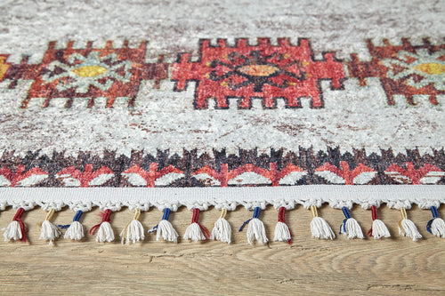 Bild 1 in Galerieansicht laden. The Ethno Expanse Machine-Washable Rug (JR5046) features red, yellow, and black geometric patterns with white fringes accented by red and blue threads—ideal for high-traffic areas and shown on a wooden floor.