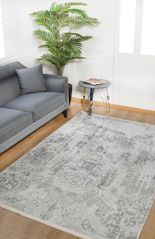 Load image 1 in gallery view. A modern living room with a gray sofa, the Faint Memories - Washable Rug - JR1437 in gray-anthracite, a round glass side table with magazines, and a tall potted plant near white paneled doors.