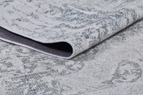 Load image 1 in gallery view. A close-up of the Faint Memories - Washable Rug - JR1437 in gray-anthracite, featuring a folded corner that shows its darker underside and slightly distressed, intricate surface design.